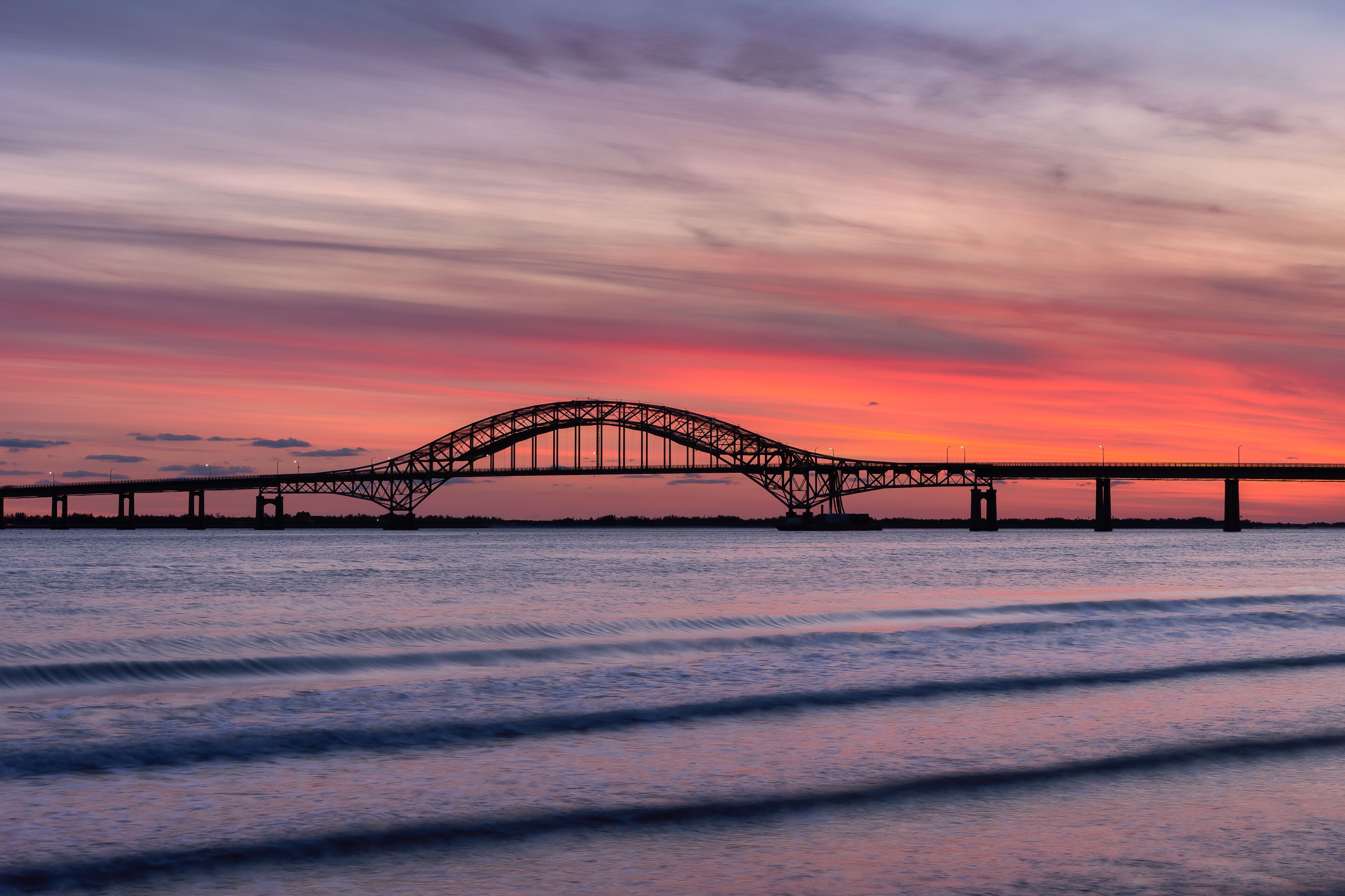 A bridge at sunset with a pink and purple sky.