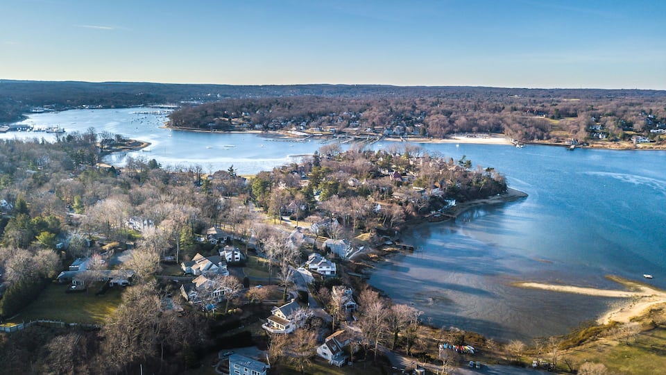A river with houses along its banks, a bridge, and a distant shoreline.