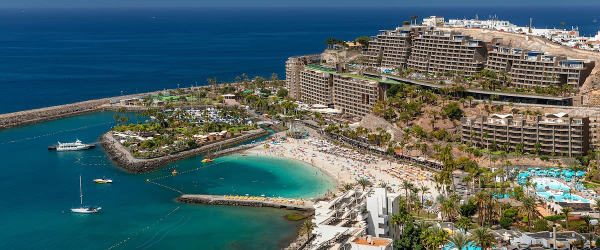 A coastal resort with a beach, a marina, and a large hotel complex.