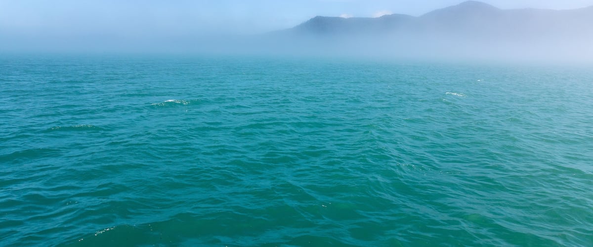 A calm sea with distant mountains and a clear sky.
