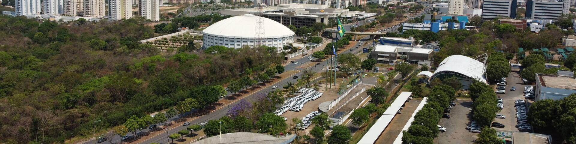 A cityscape with high-rise buildings, a large stadium, and a well-maintained park area.