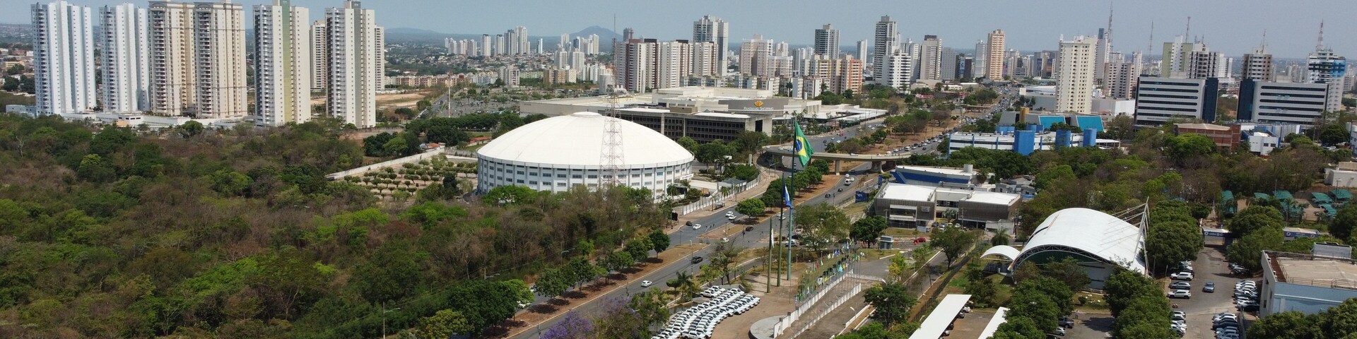 Paisagem urbana com edifícios altos, um estádio grande e uma área de parque bem cuidada.