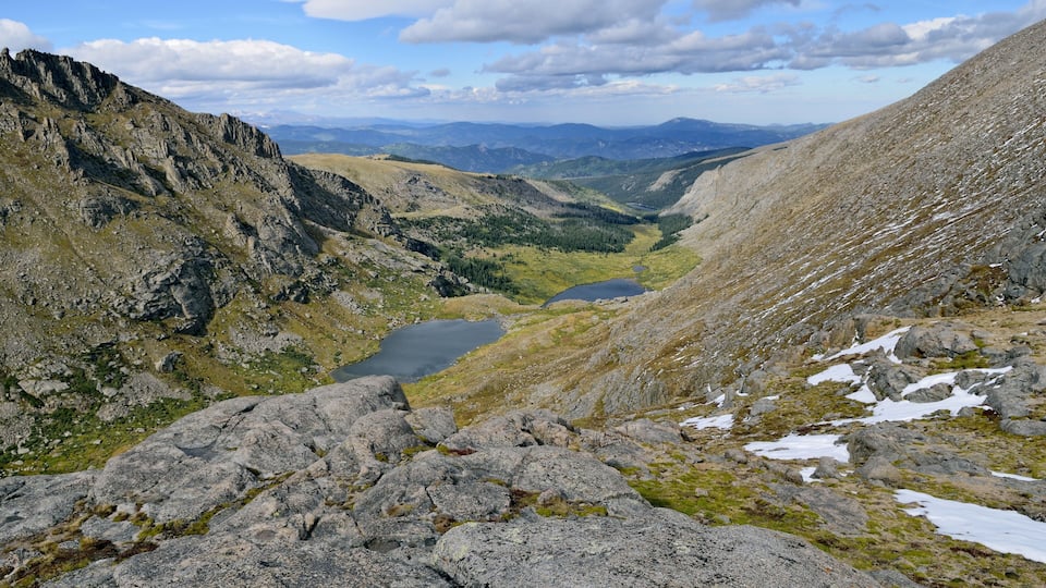A mountainous landscape with rocky terrain, a valley, and a lake.