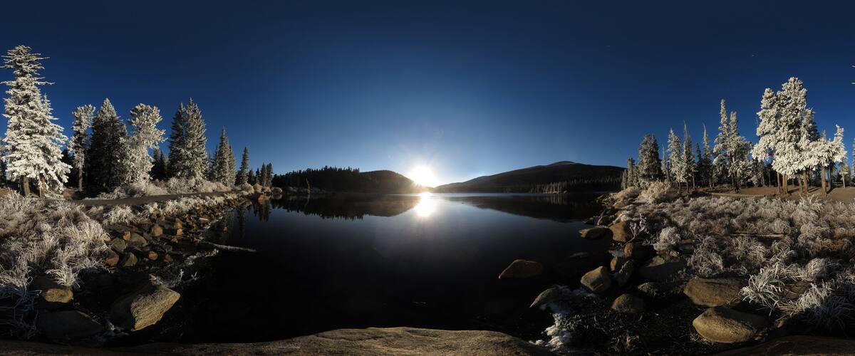 A serene lake surrounded by snow-covered trees and rocks.