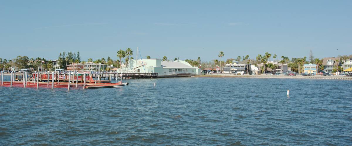 View from pier in Gulfport, Florida looking back across towards boat dock and beach. With blue water and clear blue sky on a sunny day.