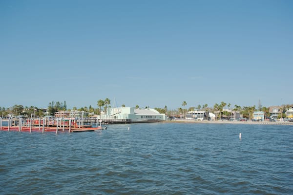 View from pier in Gulfport, Florida looking back across towards boat dock and beach. With blue water and clear blue sky on a sunny day.
