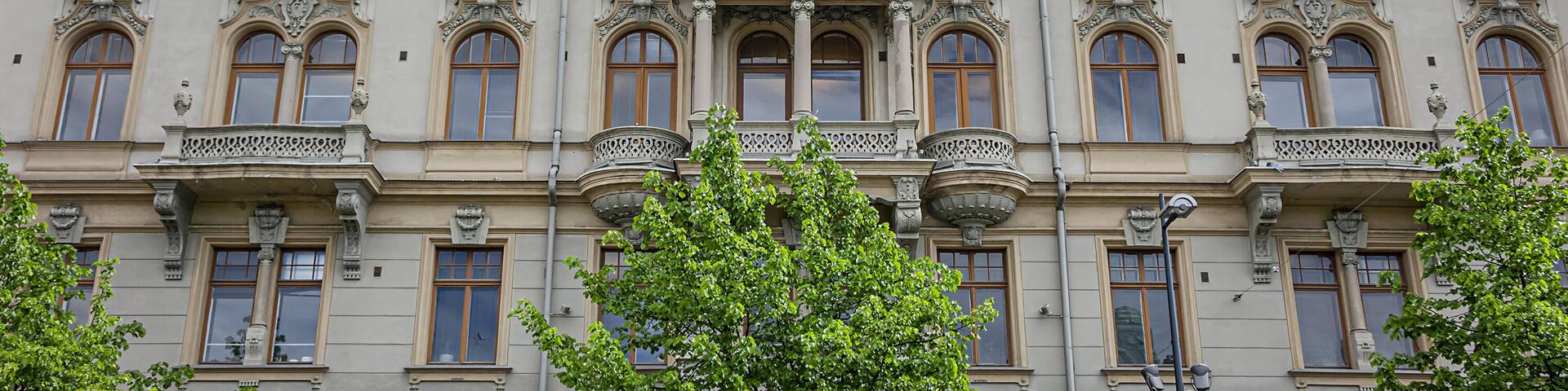Un edificio histórico con arquitectura ornamentada, que incluye un balcón y un escudo en la fachada.