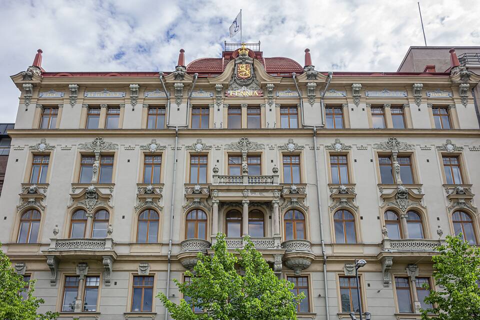A historic building with ornate architecture, including a balcony and a crest on the facade.