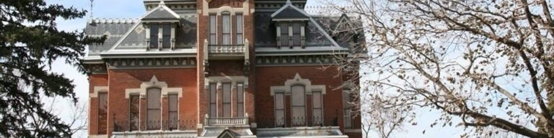 A large, historic brick building with a prominent tower and ornate detailing.