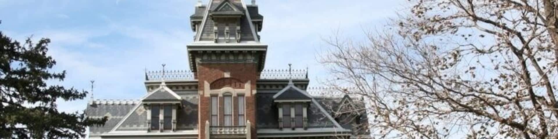 Um edifício grande e histórico de tijolo com uma torre imponente e detalhes ornamentados.