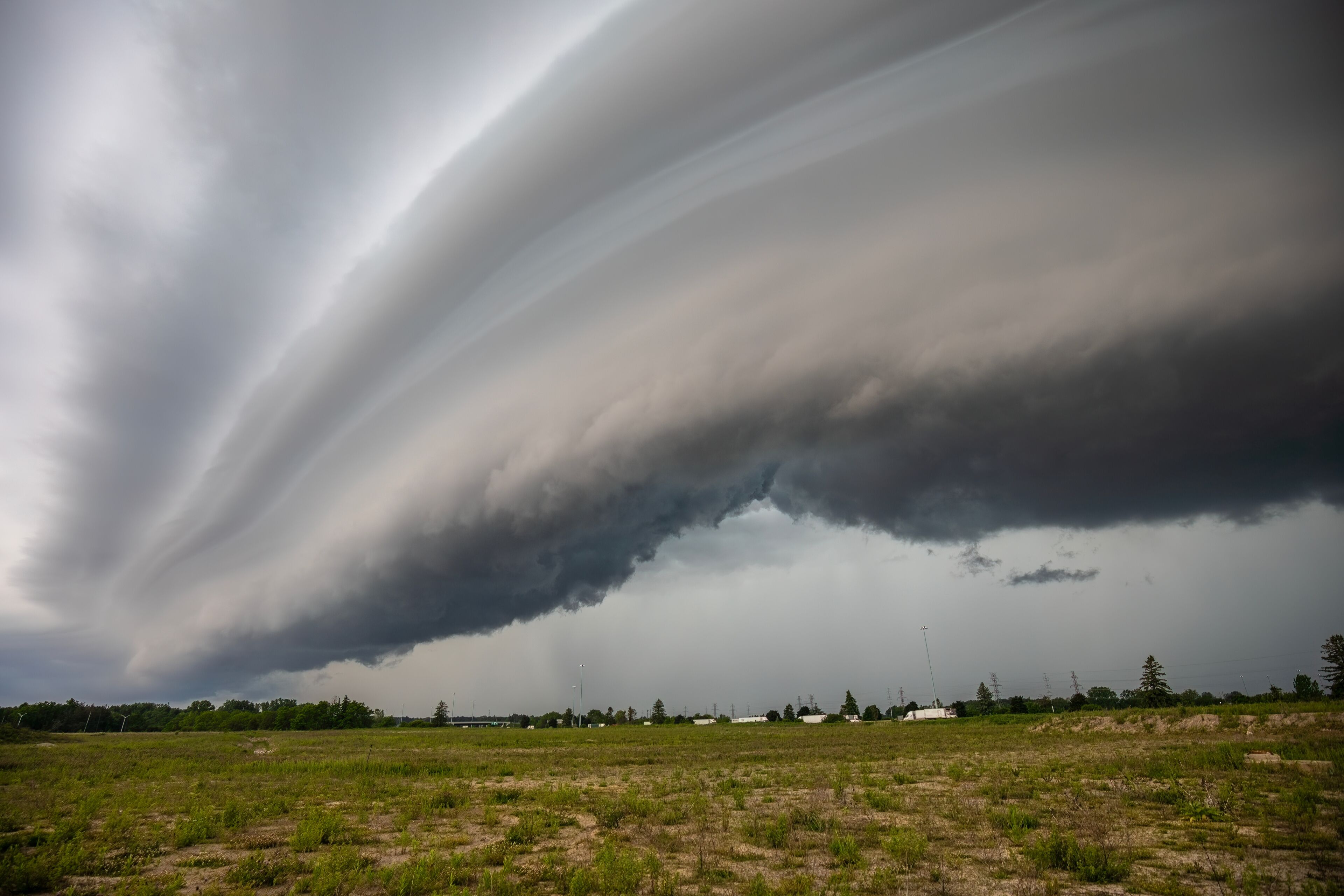 Un tornado tocando tierra en un campo rural con una nube de tormenta oscura arriba.