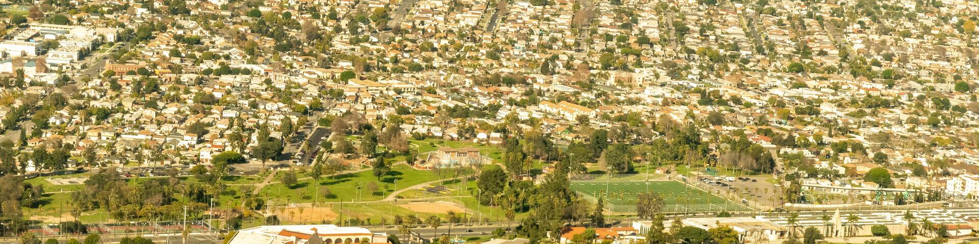 An aerial view of a residential area with a park, winding roads, and a sports field.