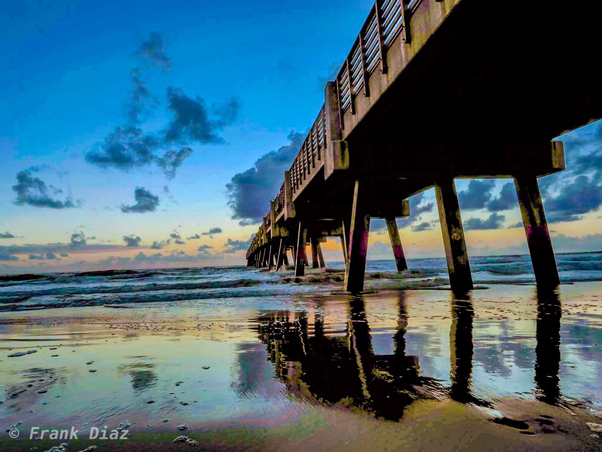 A pier extending into the ocean with a clear sky and calm waters.