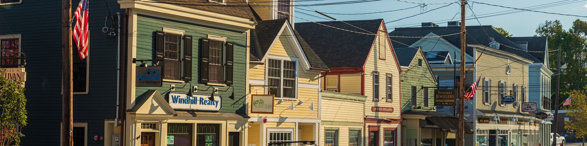 A street lined with historic buildings, including a Windhill Realty office and a jewelry store.