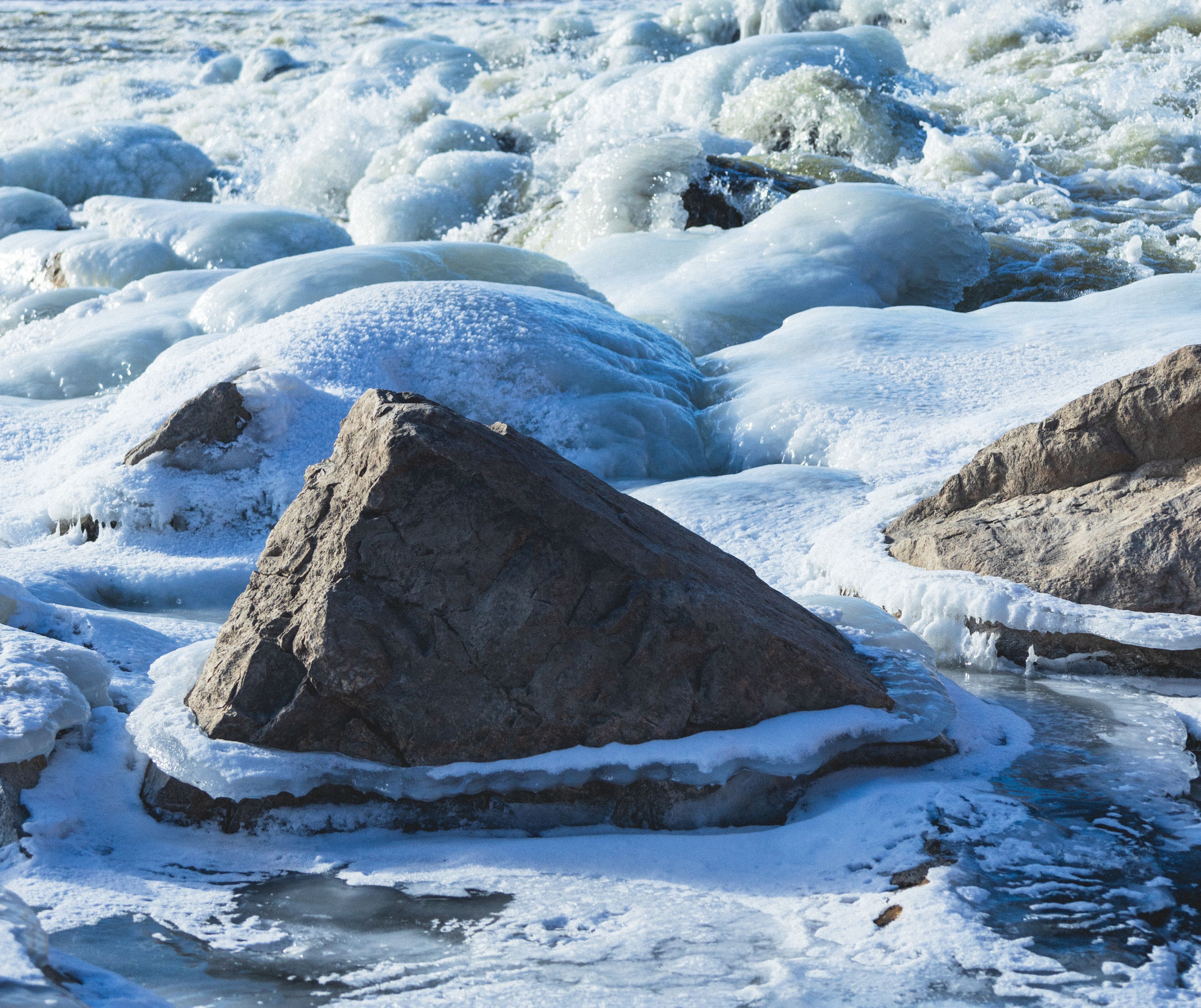 A frozen river with large ice formations and rocks.