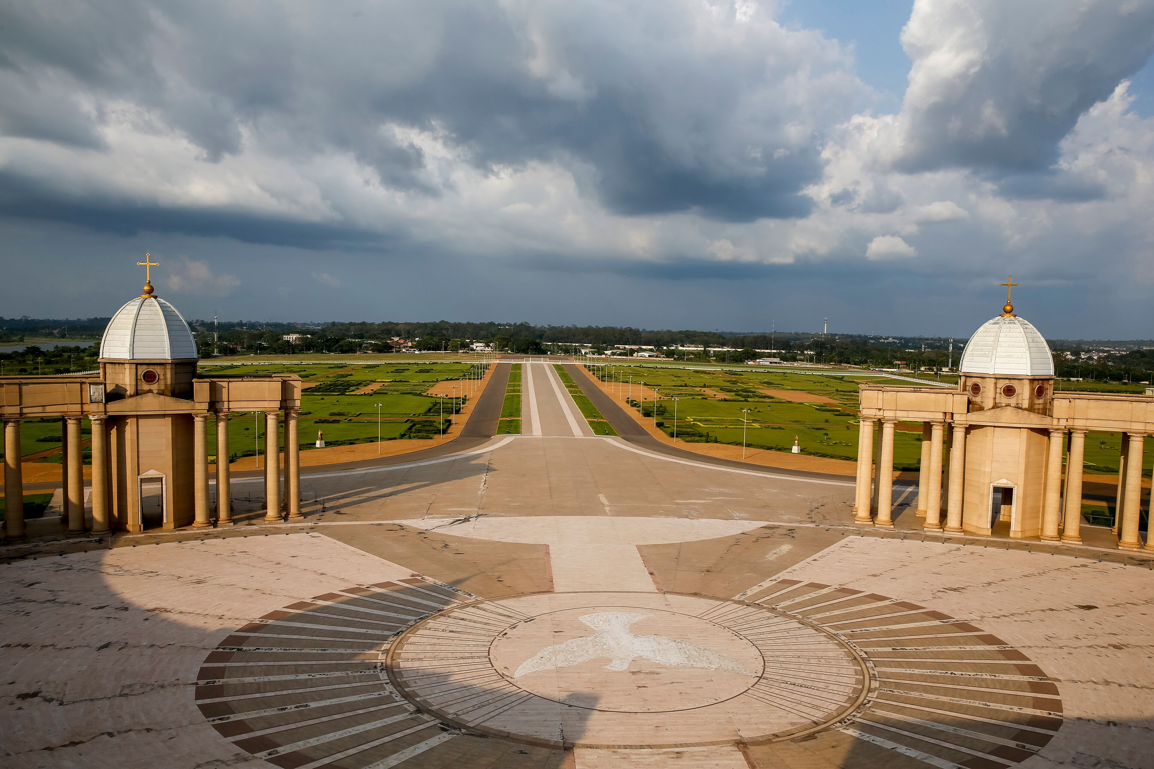 A grand architectural complex with two domed buildings, a central circular plaza, and a road leading to the horizon.