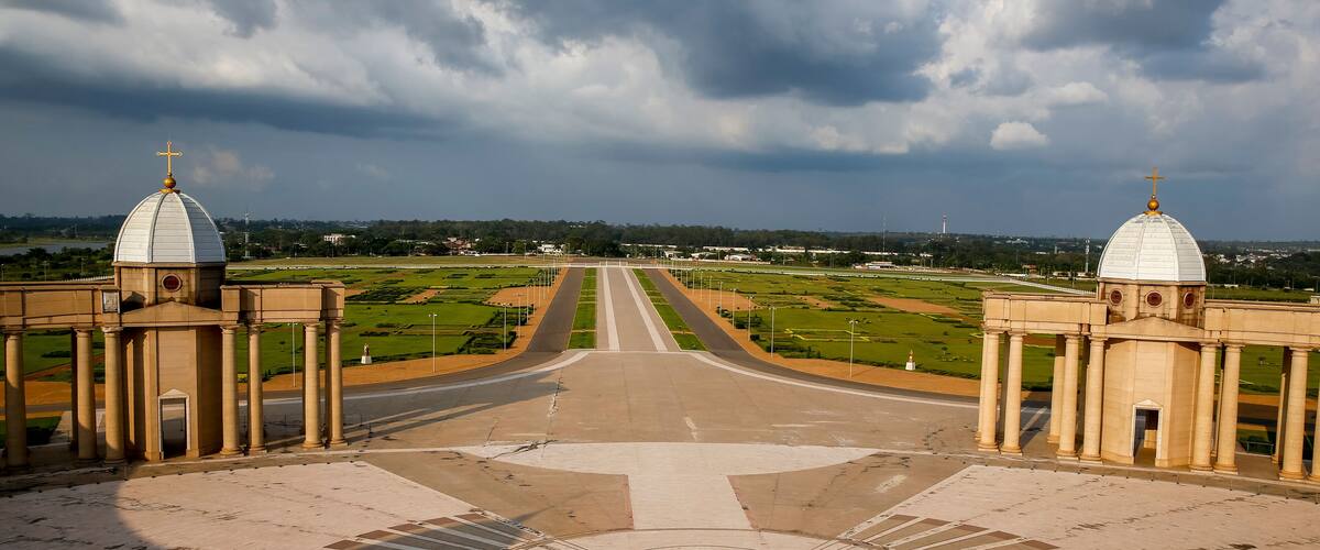 A grand architectural complex with two domed buildings, a central circular plaza, and a road leading to the horizon.