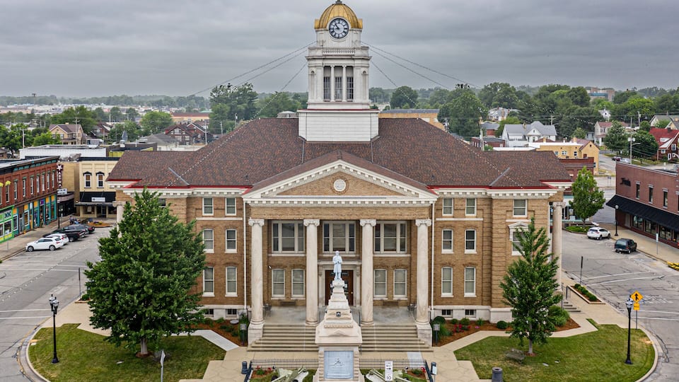 A historic building with a clock tower, surrounded by a well-maintained lawn and a parking lot.
