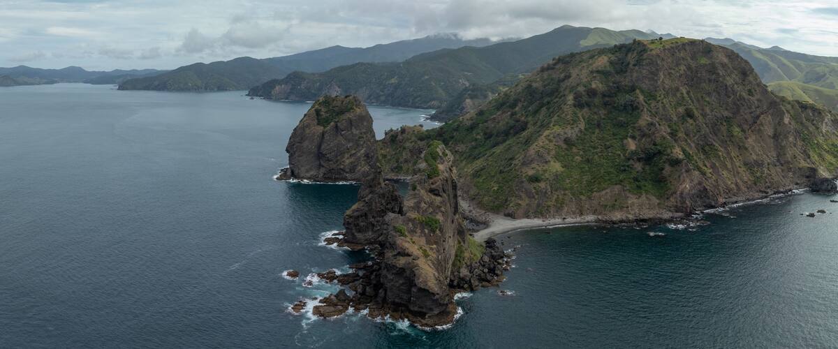 A coastal landscape with rugged cliffs, a small beach, and a large body of water.