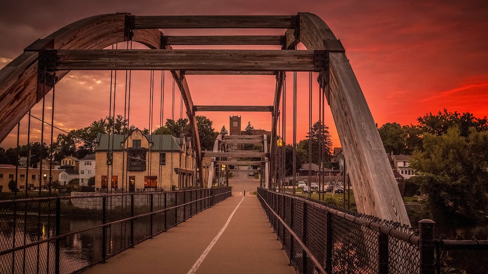Eine Brücke mit Metallstreben und einem Gehweg, vor einem Sonnenuntergangshimmel.