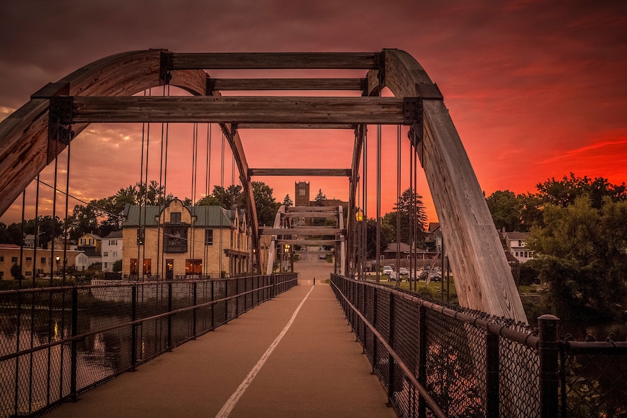 A bridge with a metal framework and a walkway, set against a sunset sky.