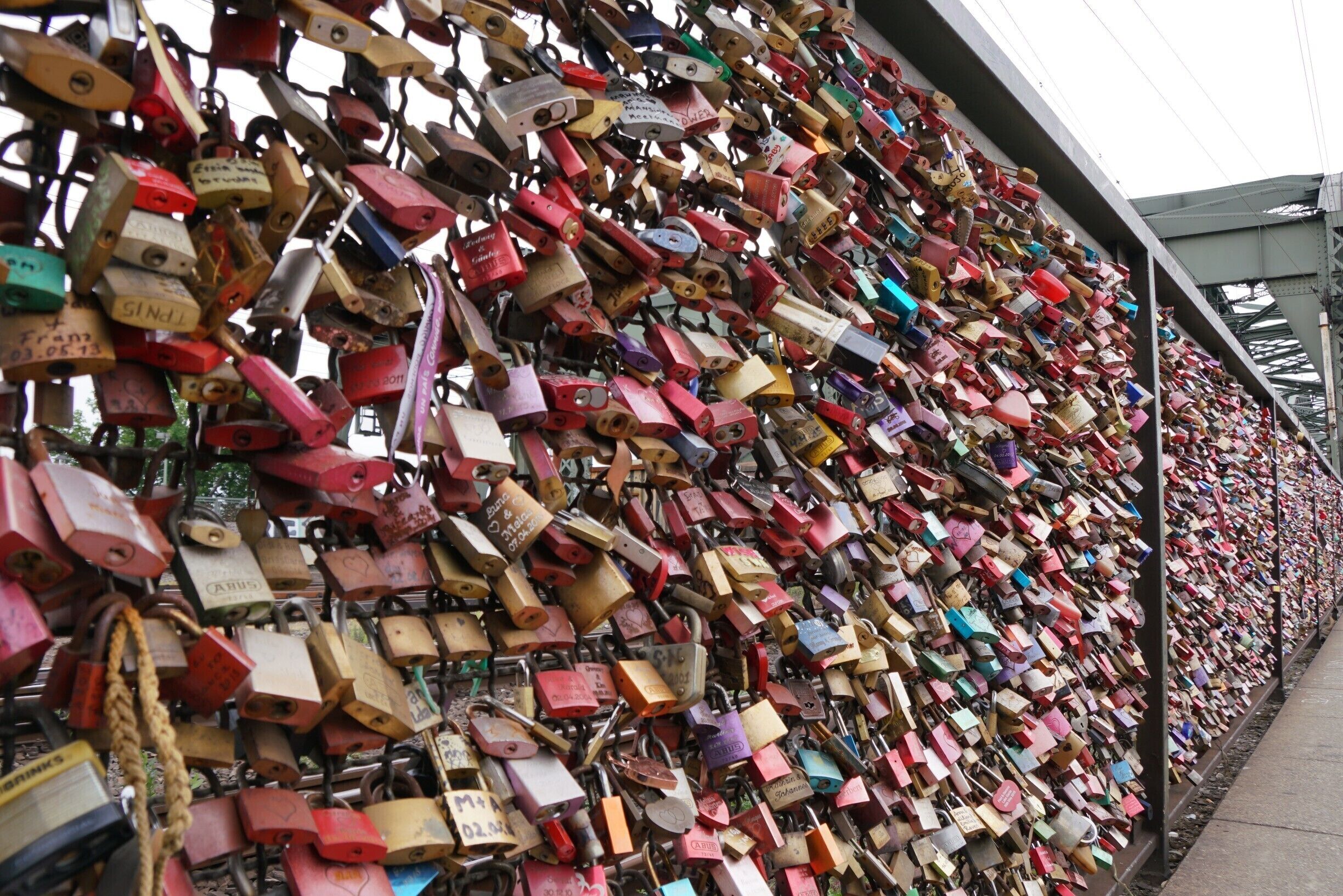 Padlock bridge in Cologne.  Despite it appearing there is no room for another lock when looking at it straight on, there is still space on here for more locks.  This entire side of the bridge is full like this and now the other side of the bridge and the entrance and exit points are starting to fill up too.

Easily accessed from the Cathedral / Central Train Station on foot.

I wonder how many of these couples are still together...? 