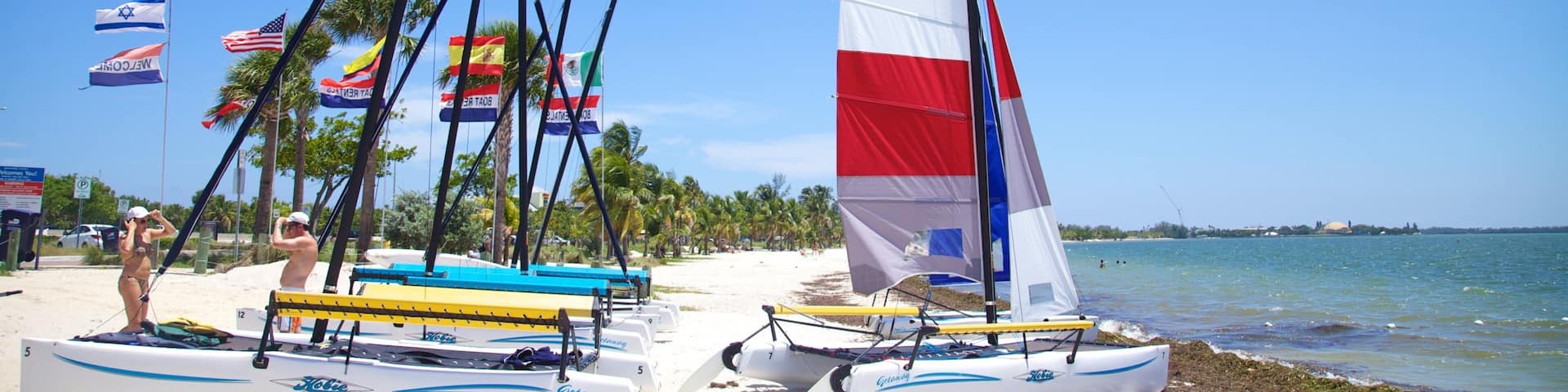 Sunlit Key Biscayne beach with colorful sailboats and vibrant flags on a clear day in Florida