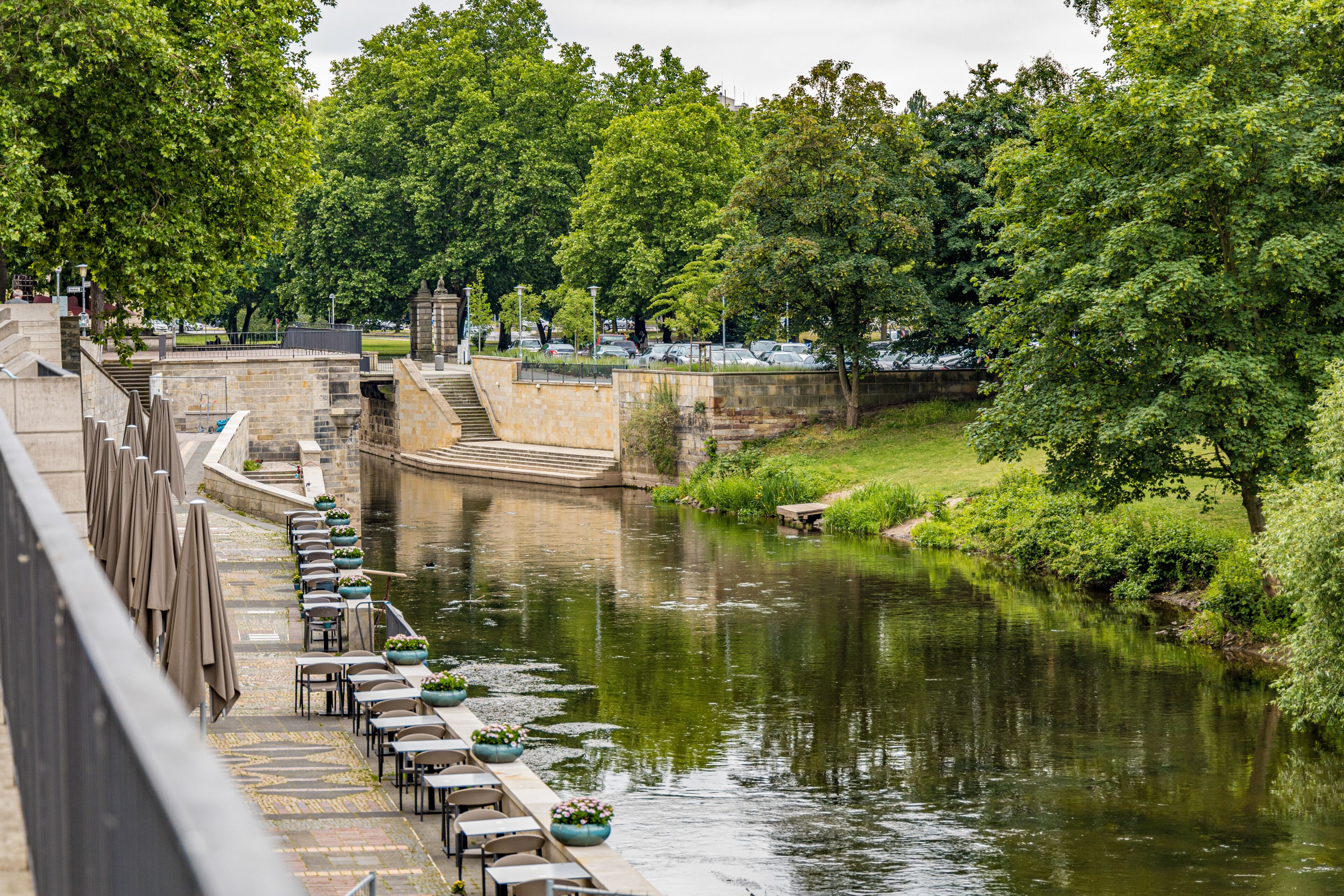 A river with a bridge and trees on both sides in Hanover Germany. The water is calm and the trees are green