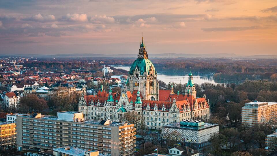 A cityscape with a prominent cathedral with a green dome, surrounded by historic buildings and a river.