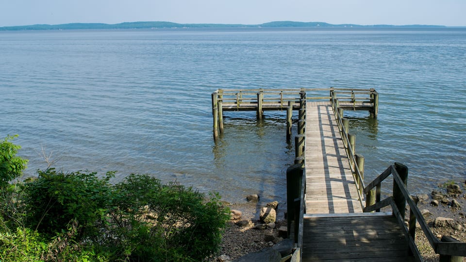 A wooden pier extending into calm water with distant hills.