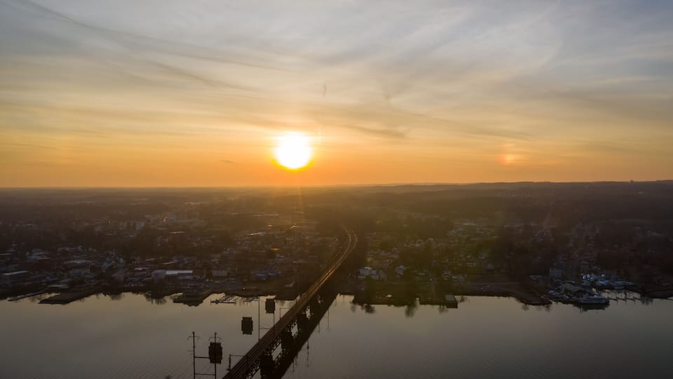 A sunrise over a cityscape with a bridge reflecting in the water.