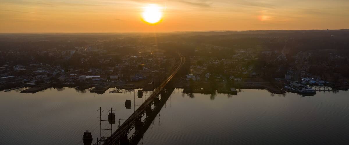 A sunrise over a cityscape with a bridge reflecting in the water.