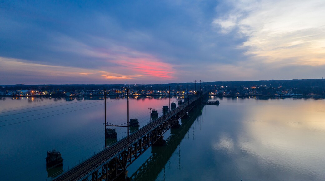 Aerial view of a bridge spanning tranquil waters reflecting the colorful twilight sky, its steel structure contrasting with the soft hues of the horizon, Perryville, Maryland, United States.