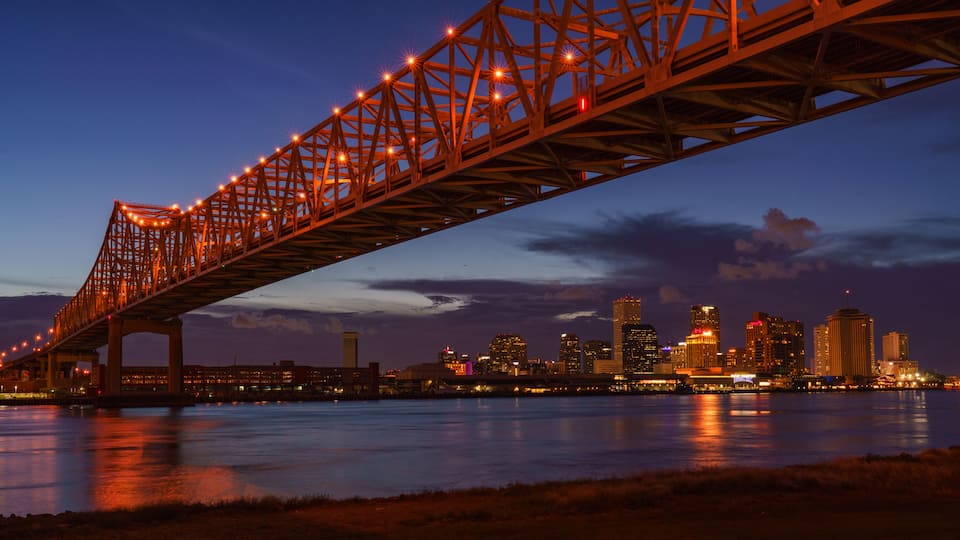 A bridge spanning a river with a city skyline in the background.
