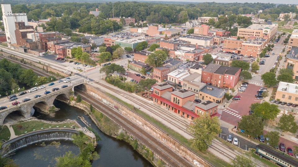 A river running through a town with a bridge, train tracks, and various buildings.
