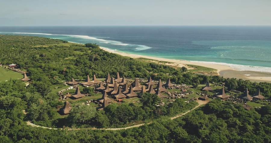 Traditional rural houses at Kodi village, Sumba Island, Indonesia. Aerial view of tropic countryside with buildings landmark at sea bay coast. Cinematic drone shot of summer vacation