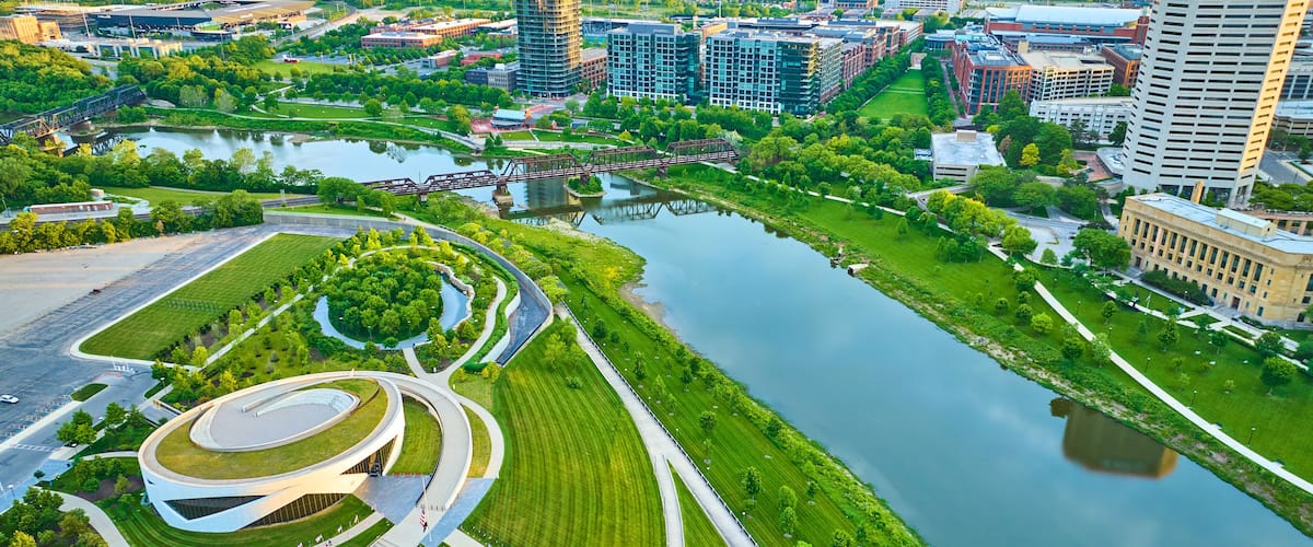 A river with a bridge, a circular park, and surrounding buildings.