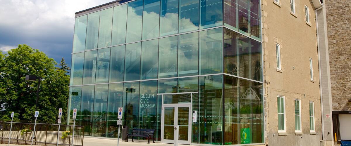 A modern glass building with a sign reading "Guelph Civic Museum" and a stone building to the right.