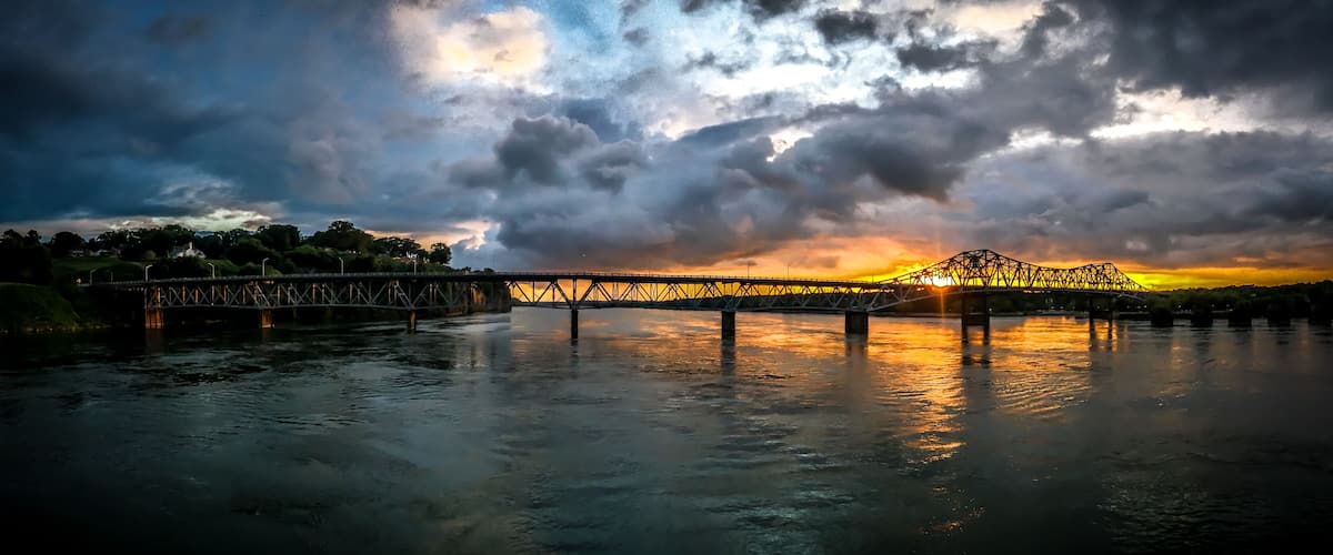 A bridge over a river with a sunset in the background.