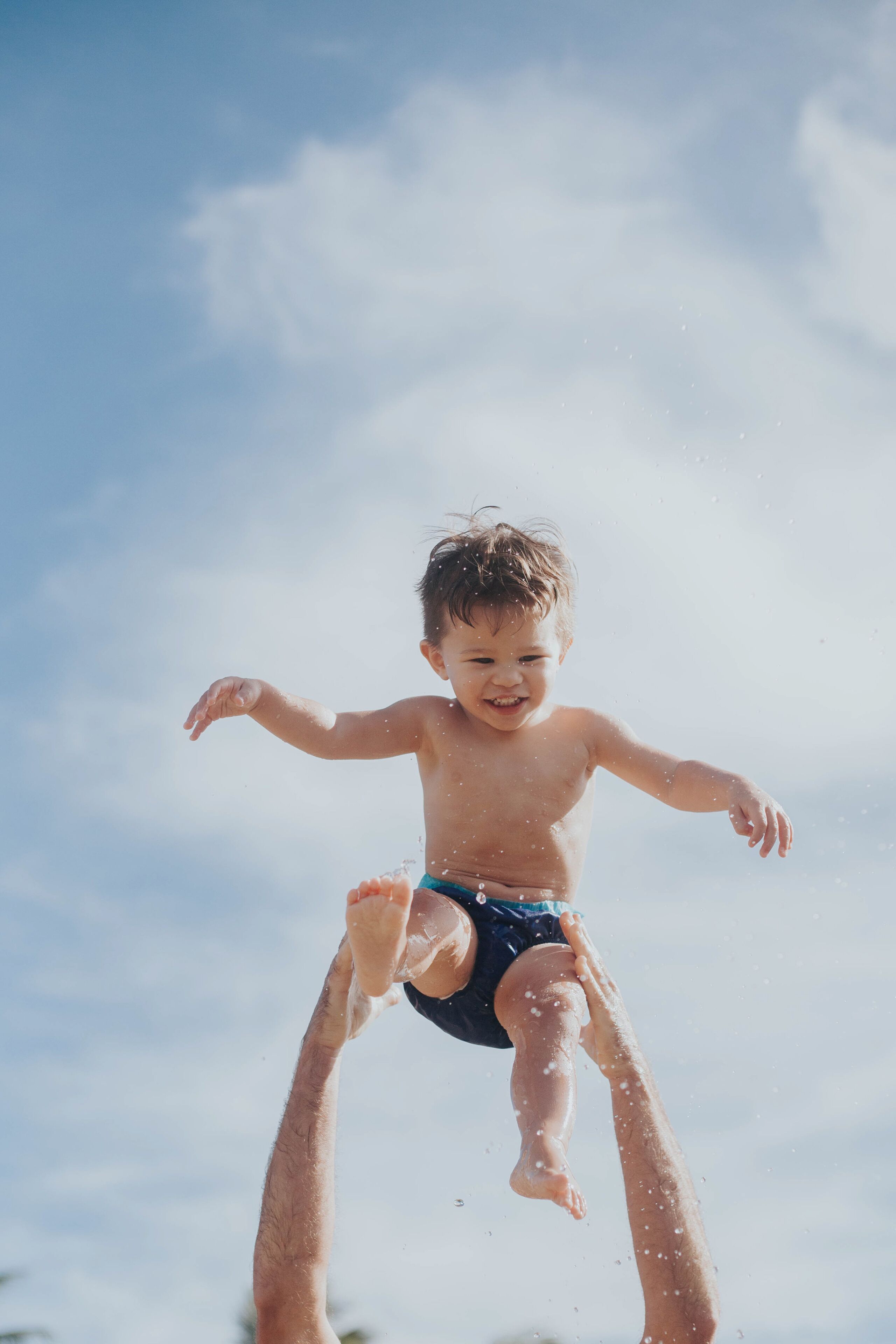 A child jumping in the air with a clear blue sky in the background.