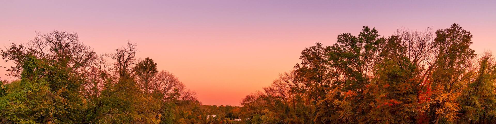 A river reflecting trees and a sunset sky.