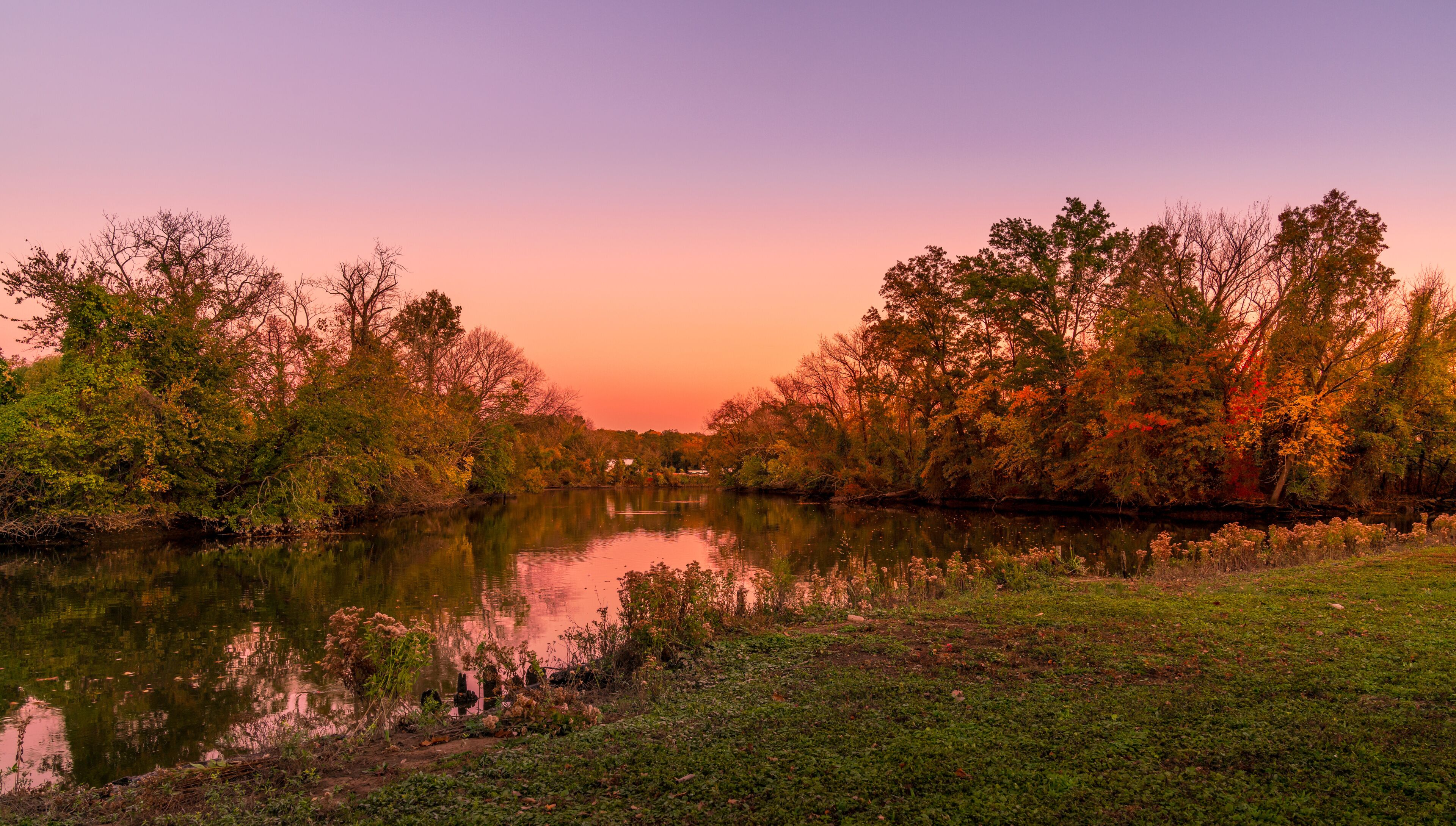 A river reflecting trees and a sunset sky.