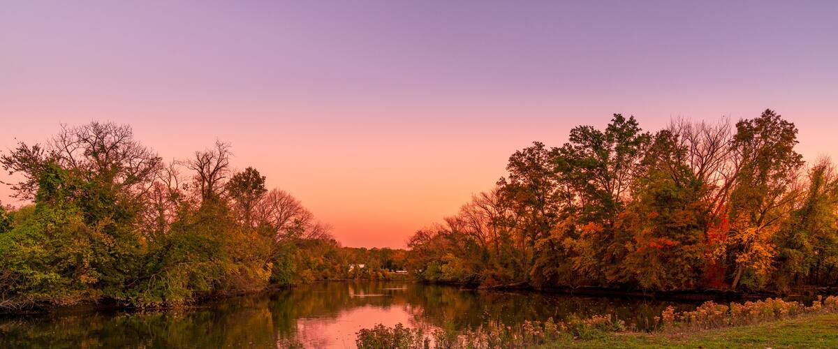 A river reflecting trees and a sunset sky.