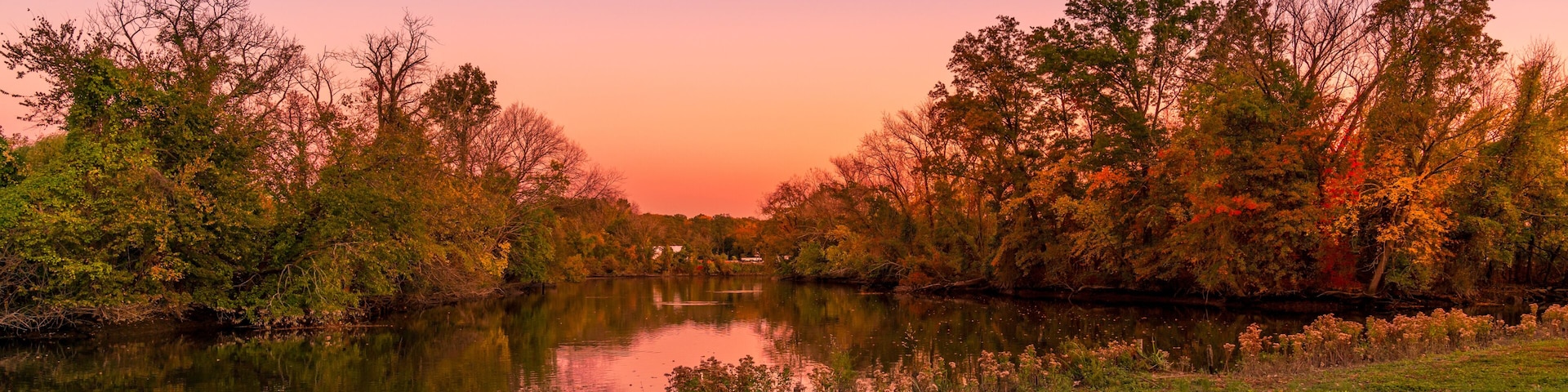 A river reflecting trees and a sunset sky.