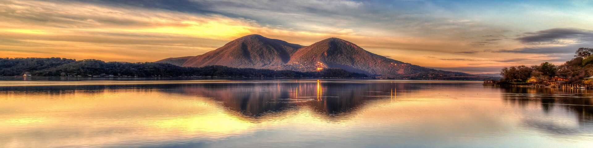 Una cordillera reflejada en un lago tranquilo con un cielo al atardecer.