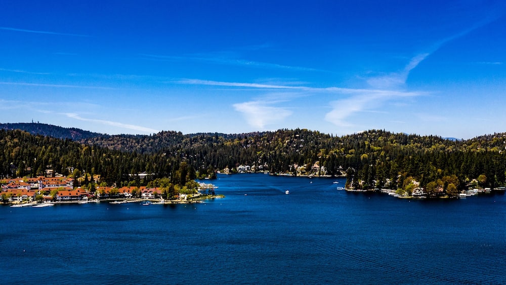 A lake surrounded by forested hills and a small town with red-roofed buildings.