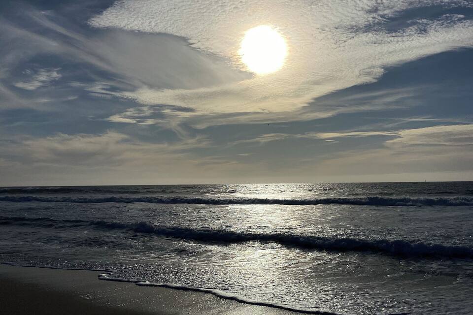 Una playa con olas y un sol poniéndose.