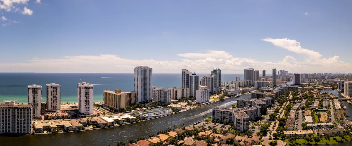 A coastal cityscape with high-rise buildings, a river, and a clear blue sky.