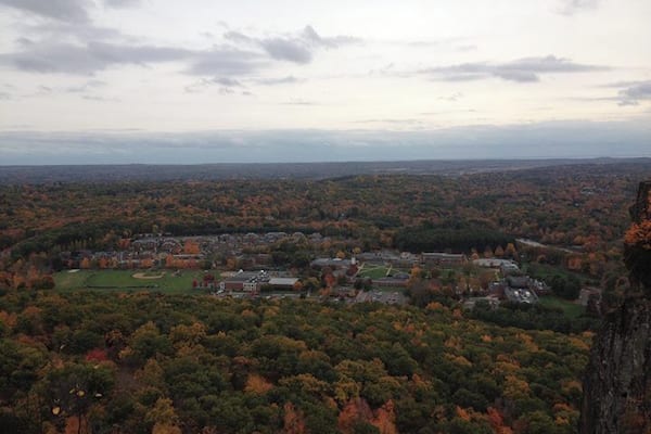 A town surrounded by autumn foliage, with a prominent hill in the foreground.