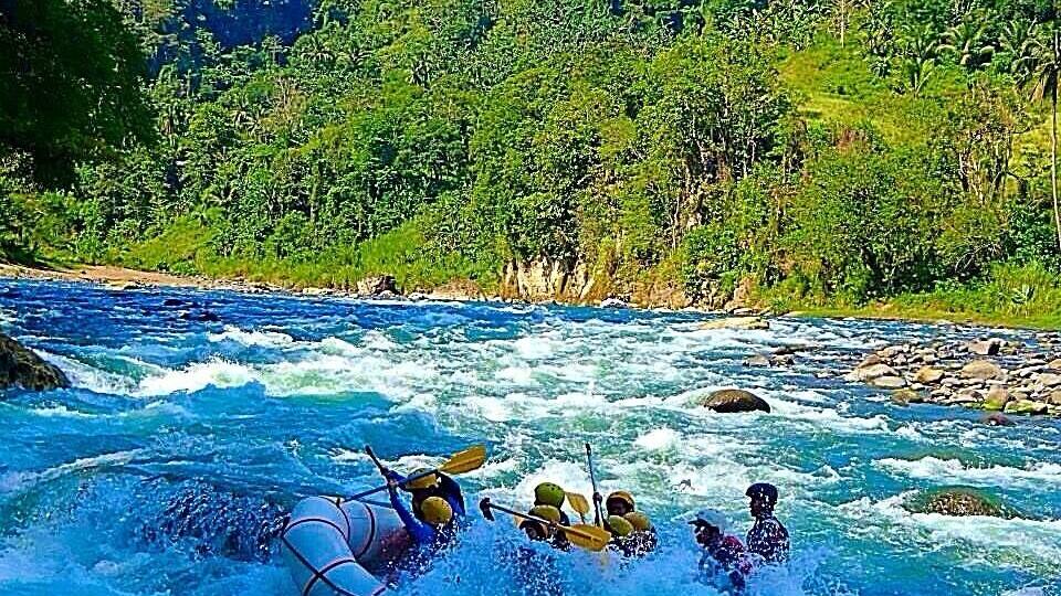 A group of people rafting on a river surrounded by lush greenery.